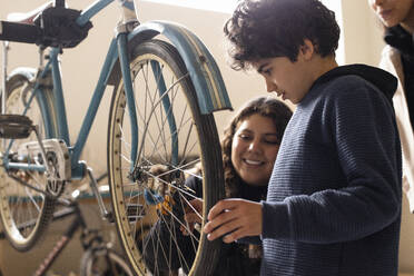 Junge lernt Fahrradreparatur mit einer Technikerin im Recyclingzentrum - MASF38494