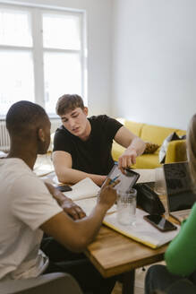 Male friends studying together while using digital tablet at home - MASF38518