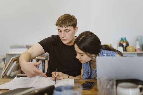 Man pointing at book while studying together - MASF38535