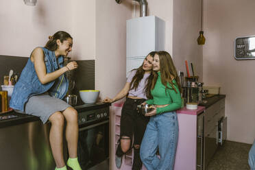 Smiling young female friends talking in kitchen at home - MASF38554