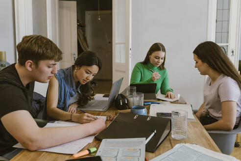 Young man and women doing homework at dining table - MASF38565