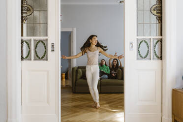 Smiling young women cheering friend dancing in living room at home - MASF38569