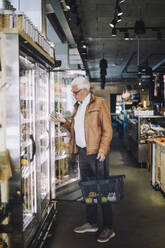 Full length of senior man analyzing organic vegetable at grocery store - MASF38593