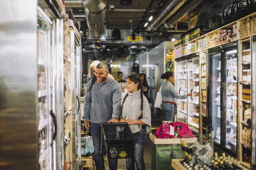 Smiling father and daughter shopping for groceries at convenience store - MASF38602