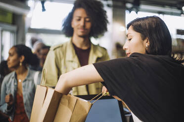 Saleswoman packing bag while customer standing at grocery store checkout - MASF38617