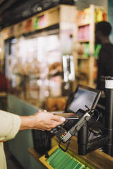 Hand of young male customer paying through smart phone at store checkout - MASF38619