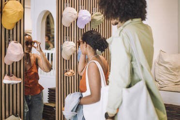 Woman trying sunglasses while standing by man at fashion boutique - MASF38670