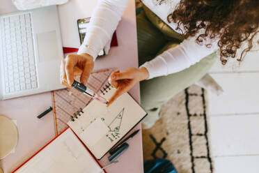 High angle view of woman using glucometer while doing homework at table - MASF38718