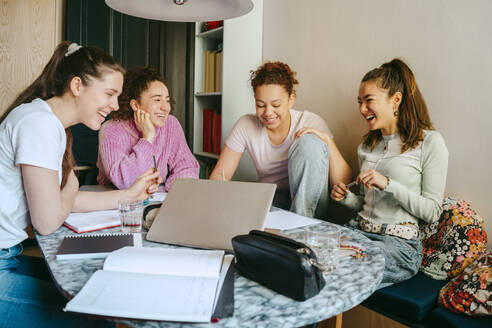 Cheerful female friends studying together while doing homework - MASF38748