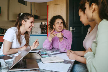 Happy female friends studying together while doing homework - MASF38749