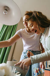 Low angle view of cheerful female friends preparing lunch in bowl at home - MASF38759