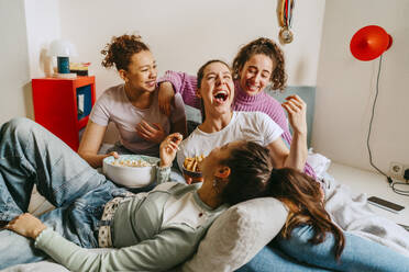 Female friends having fun and enjoying snacks at home - MASF38765