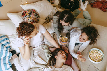 Directly above shot of female friends having snacks while spending leisure time at home - MASF38779