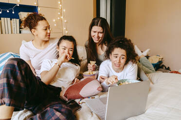 Weibliche Freunde machen Grimassen, während sie zu Hause auf dem Laptop einen Film ansehen - MASF38782