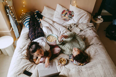 High angle view of female friends spending leisure time on bed at home - MASF38785