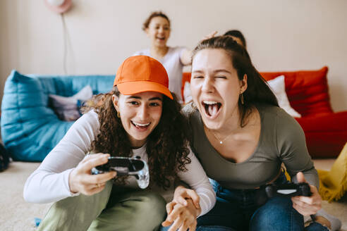 Playful young female friends playing video game at home - MASF38820