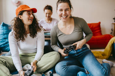 Happy female friends playing video game at home - MASF38822