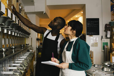 Multiracial colleagues checking inventory in food store - MASF38856