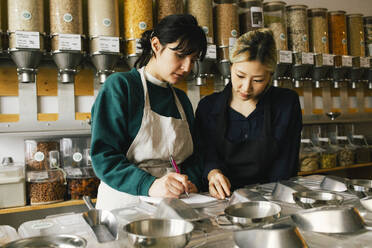 Multiracial female colleagues taking inventory in food store - MASF38857