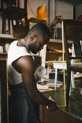 Male entrepreneur measuring wooden chair at workshop - MASF38907