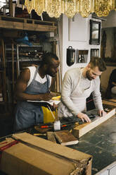 Multiracial male entrepreneurs working at upcycling workshop - MASF38908