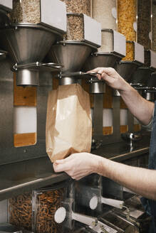 Cropped image of owner filling food in paper bag while working in store - MASF38914