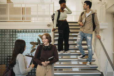 Multiracial male and female students with backpacks talking in university - MASF39022