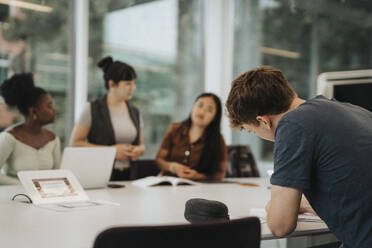 Young male student studying at table in university - MASF39044