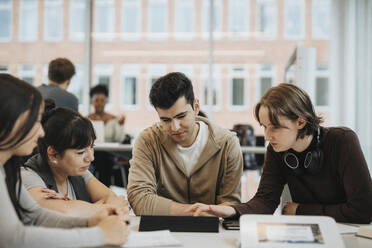 Multiracial students discussing with teacher over tablet PC in university - MASF39048