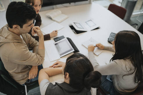 High angle view of students discussing at table in university - MASF39050