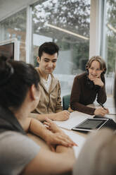 Smiling male and female students studying together at university - MASF39051