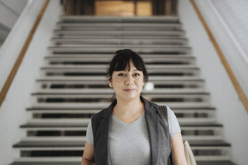 Porträt einer selbstbewussten Professorin, die an der Treppe einer Universität steht - MASF39068