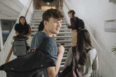 Porträt eines lächelnden männlichen Studenten mit Freunden an der Universität - MASF39073