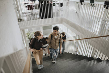 High angle view of students talking while moving up on steps in university - MASF39078
