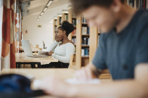 Student yawning while studying in library at university - MASF39087