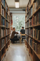 Professor explaining student studying in library at university - MASF39111