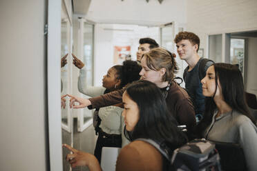 Multiracial students checking result on bulletin board in university - MASF39116