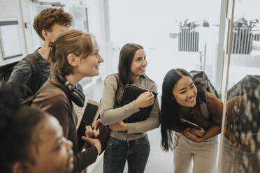 Cheerful multiracial male and female students checking result on bulletin board in university - MASF39119