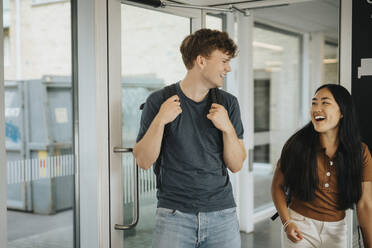 Cheerful male and female students entering classroom in university - MASF39124