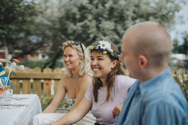 Lächelnde junge Frau, die ein Diadem trägt, während sie sich mit Freunden bei einer Dinnerparty im Café amüsiert - MASF39138