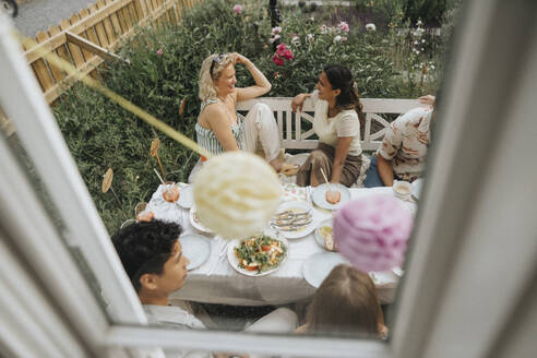 Hohe Winkel Ansicht der glücklichen Freunde feiern Abendessen Partei durch Cafe Fenster gesehen - MASF39157