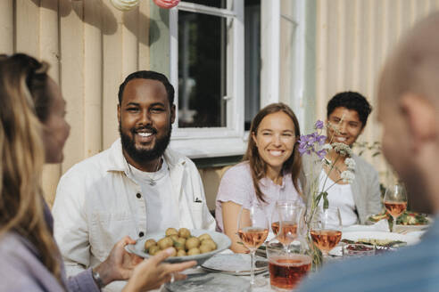 Frau serviert männlichen und weiblichen Freunden Babykartoffeln während einer Dinnerparty im Cafe - MASF39168