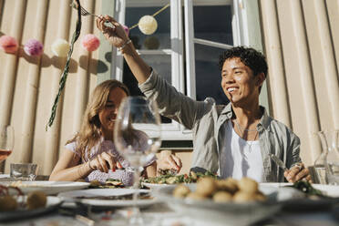 Happy young man enjoying food with friend during dinner party at cafe - MASF39183