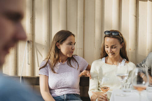 Junge Frau im Gespräch mit einer Freundin während einer Dinnerparty im Café - MASF39189