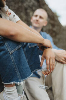 Junger Mann hält Wein im Glas und sitzt mit einem Freund zusammen - MASF39192