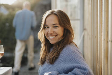 Side view portrait of smiling woman wearing sweater during dinner party at cafe - MASF39201