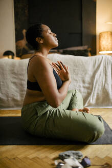 Side view of young woman meditating in bedroom at home - MASF39270