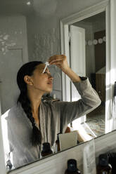 Young woman applying cream on face - MASF39314