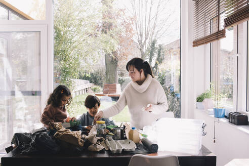 Woman separating waste with son and daughter at home - MASF39355