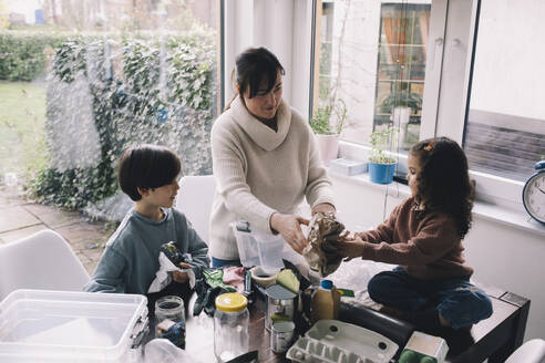 Woman separating waste with children at home - MASF39356